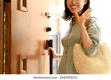 Young Asian woman opening the front door of a residential building - Powered by Shutterstock