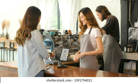 Young Asian Woman Ordering Coffee By Digital Tablet With Barista, Waitress, Small Business Owner At Counter In Coffee Shop Cafe Background, Small Business Concept