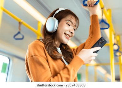 Young Asian Woman Passenger and Listening Music, Using Mobile Smartphone in Subway Sky Train. Lifestyle in City and Daily Urban Life. Transportation Concept