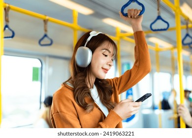 Young Asian Woman Passenger and Listening Music, Using Mobile Smartphone in Subway Sky Train. Lifestyle in City and Daily Urban Life. Transportation Concept - Powered by Shutterstock