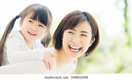 Young Asian Woman Piggybacking A Little Girl.