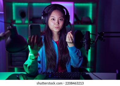 Young Asian Woman Playing Video Games With Smartphone Doing Money Gesture With Hands, Asking For Salary Payment, Millionaire Business 