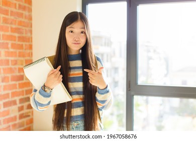 Young Asian Woman Pointing To Self With A Confused And Quizzical Look, Shocked And Surprised To Be Chosen