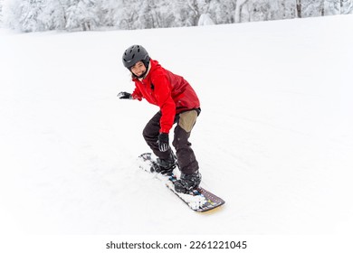 Young Asian woman practicing snowboard on snowy mountain slope at ski resort. Attractive girl enjoy outdoor active lifestyle extreme sport training freeride snowboarding on winter holiday vacation. - Powered by Shutterstock