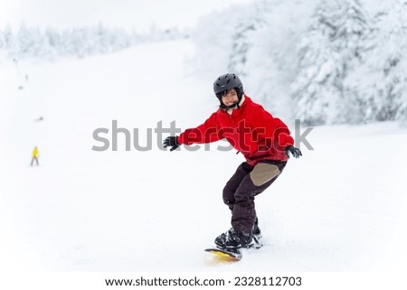 Young Asian woman practicing snowboard on snowy mountain slope at ski resort. Attractive girl enjoy outdoor active lifestyle extreme sport training freeride snowboarding on winter holiday vacation.