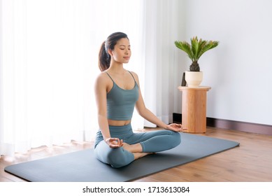 A young Asian woman practicing yoga indoors - Powered by Shutterstock