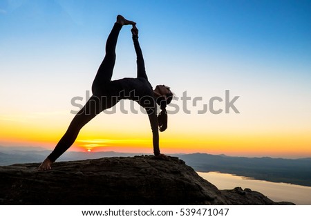 young asian woman practicing yoga warrior pose at sunset. Zen wellness and wellbeing concept.