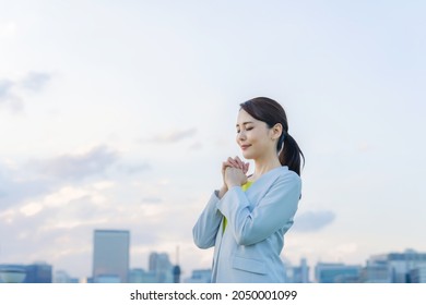 Young Asian Woman Praying In Front Of The City.