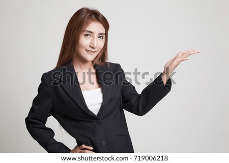 Young Asian woman present with her hand on gray background