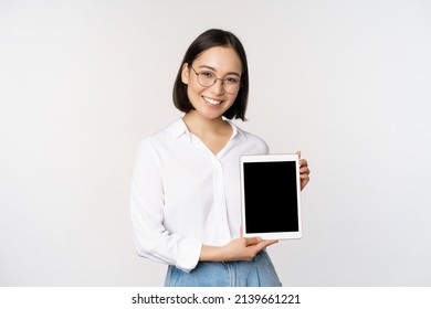 Young Asian Woman Professional Demonstrates Digital Tablet Screen, Info On Her Gadget, Smiling And Looking At Camera, Standing Over White Background