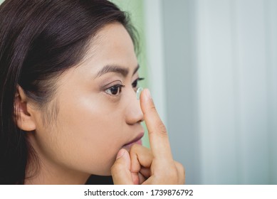 Young Asian Woman Putting Contact Lens In Right Eye.