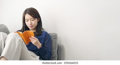 Young Asian Woman Reading A Book In The Room.