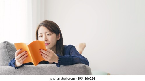 Young Asian Woman Reading A Book In The Room.