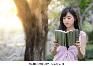 A Young Asian Woman Is Reading A Book