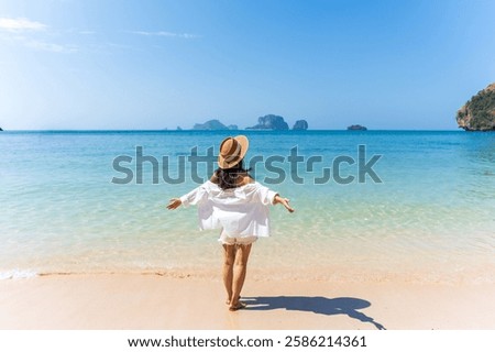 Young Asian woman relaxing and enjoying at beautiful white sand beach on sunny day, Travel on summer vacation