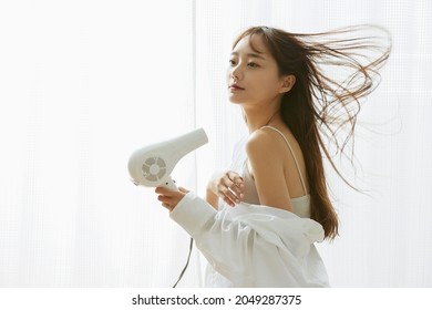 A Young Asian Woman Relaxing With A Hair Dryer