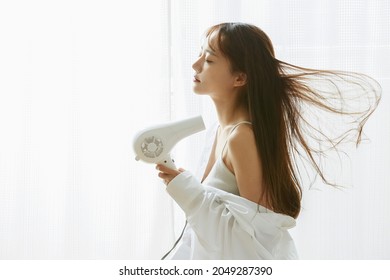 A Young Asian Woman Relaxing With A Hair Dryer