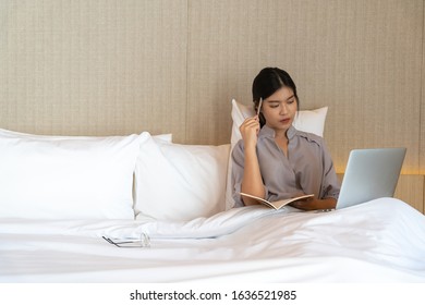 Young Asian Woman Relaxing In The Hotel And Working With Laptop On A Bed, Business Trip, Working Travel Concept