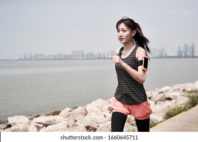 Young Asian Woman Running Jogging Outdoors By The Sea