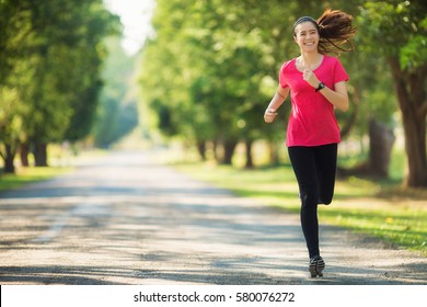 Young Asian Woman Running On The Road With Smiling Face, Healthy Lifestyle And Sport Concepts. Copy Space.