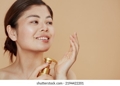 Young Asian Woman With Self Tanning Lotion On Beige Background.