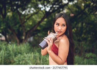 A Young Asian Woman In A Sexy Revealing Top Sipping On A Tumbler Of Iced Coffee. Confident, Liberated And Attractive.