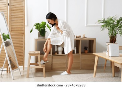 Young Asian woman with shaved legs at home