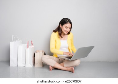 Young Asian Woman Shopping Online At Home Sitting Besides Row Of Shopping Bags