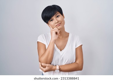Young asian woman with short hair standing over isolated background with hand on chin thinking about question, pensive expression. smiling with thoughtful face. doubt concept.  - Shutterstock ID 2313388841