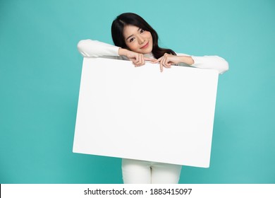 Young asian woman showing and holding blank white billboard isolated on green background - Powered by Shutterstock