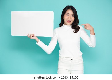 Young asian woman showing and holding blank white billboard isolated on green background