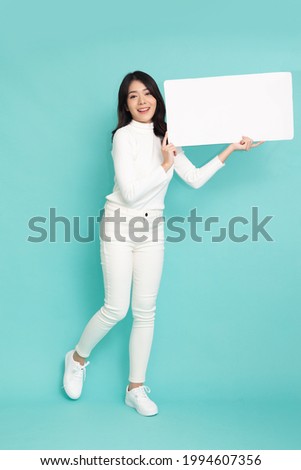 Young asian woman showing and holding blank white billboard isolated on green background, Full body composition