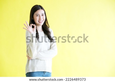 Young asian woman showing ok hand sign and smiling while standing over isolated yellow background, Happy asia female showing ok hand, Positive people gesture