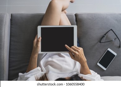Young asian woman sitting on sofa and using tablet at home