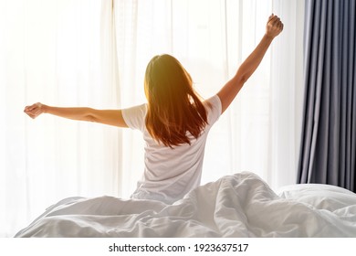 Young Asian Woman Sitting On The Bed And Stretch Oneself In The Morning At Home