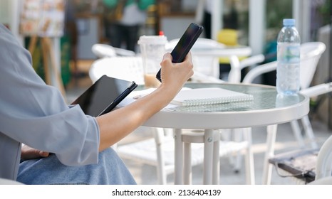 Young Asian Woman Sitting In Outdoor Cafe And Using Mobile Phone And Tablet Computer Working Part Time 