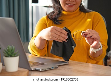 A Young Asian Woman Sitting At Working Desk With Laptop Use Micro Fiber Clothe Clean Up. Eyes Glasses To Remove The Dust On The Lens. 