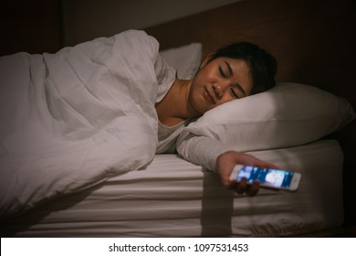 Young asian woman sleep on bed late at night holding mobile phone and tired in internet communication overuse and smartphone addiction.