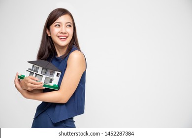 Young Asian woman smiling and hugging dream house sample model isolated over white background, Real estate and home insurance concept - Shutterstock ID 1452287384
