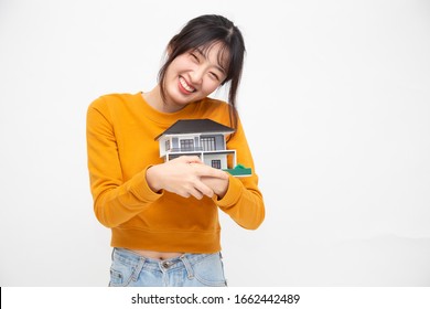 Young Asian Woman Smiling And Hugging Dream House Sample Model Isolated Over White Background, Real Estate And Home Insurance Concept