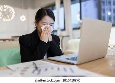 Young Asian Woman Sneezing While She  Woking On Laptop At Home.