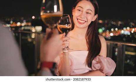 Young asian woman with sparklers is dancing and celebrating a new year. Fireworks, bengal lights in slow motion. Having fun at rooftop in the city.Happy interracial couple with glasses of wine .