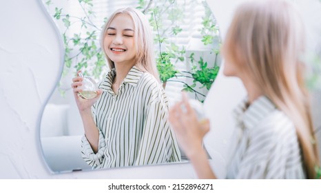 Young Asian Woman Spraying Perfume In Front Of Mirror
