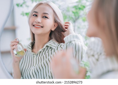 Young Asian Woman Spraying Perfume In Front Of Mirror
