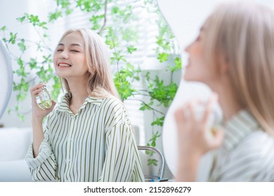 Young Asian Woman Spraying Perfume In Front Of Mirror
