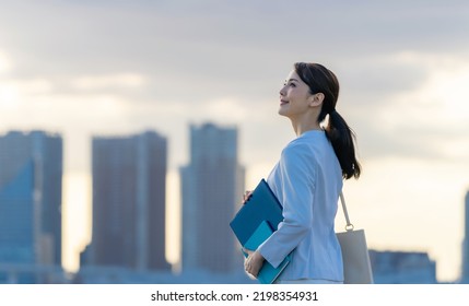 Young Asian woman standing in front of the city. - Shutterstock ID 2198354931
