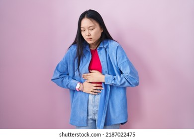 Young Asian Woman Standing Over Pink Background With Hand On Stomach Because Indigestion, Painful Illness Feeling Unwell. Ache Concept. 