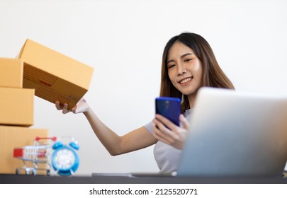 Young Asian Woman Starting A Small E-commerce Business Working On Laptop Internet And Talking To Customers Over The Phone.