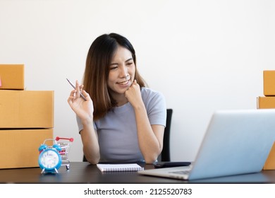 A Young Asian Woman Starting A Small E-commerce Business Is Working On A Laptop And Chatting With Customers Over The Internet.