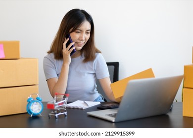 Young Asian Woman Starting A Small E-commerce Business Working On Laptop Internet And Talking To Customers Over The Phone.